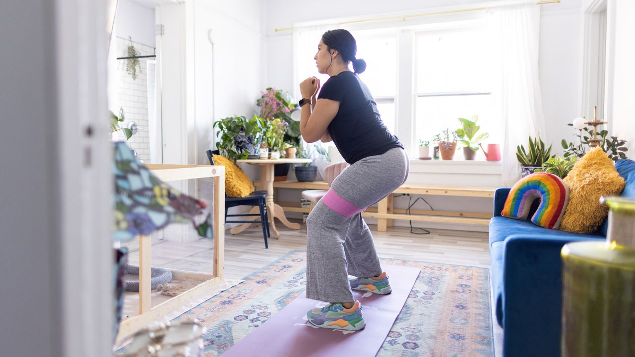 Woman doing full-body resistance band workout at home