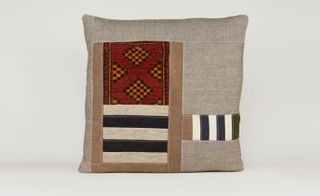 Brown cushion with black and white patches and a section of red and yellow geometric patterning