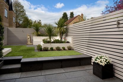 A modern backyard with a grey horizontal slatted fence