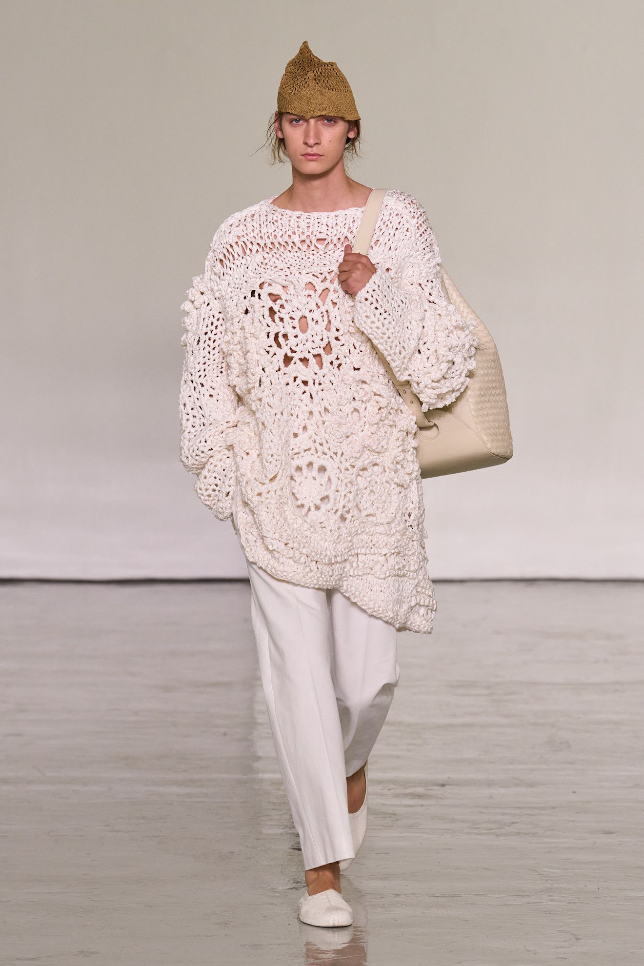 A model walks the runway at Bottega Veneta's spring/summer 2027 Milan Fashion Week show wearing a hand-knit crochet sweater with white poplin pants and white flats.