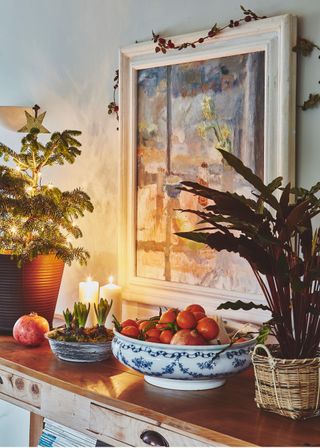 detail of painting and hyacinth bulbs on a sideboard with small christmas tree fruit and plant