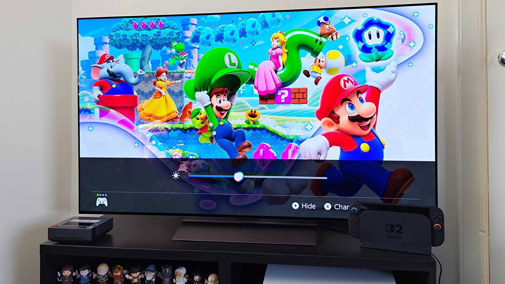 Switch 2 connected to LG OLED C4 on black TV bench with Mario Odyssey artwork on screen and white point brightness slider active.