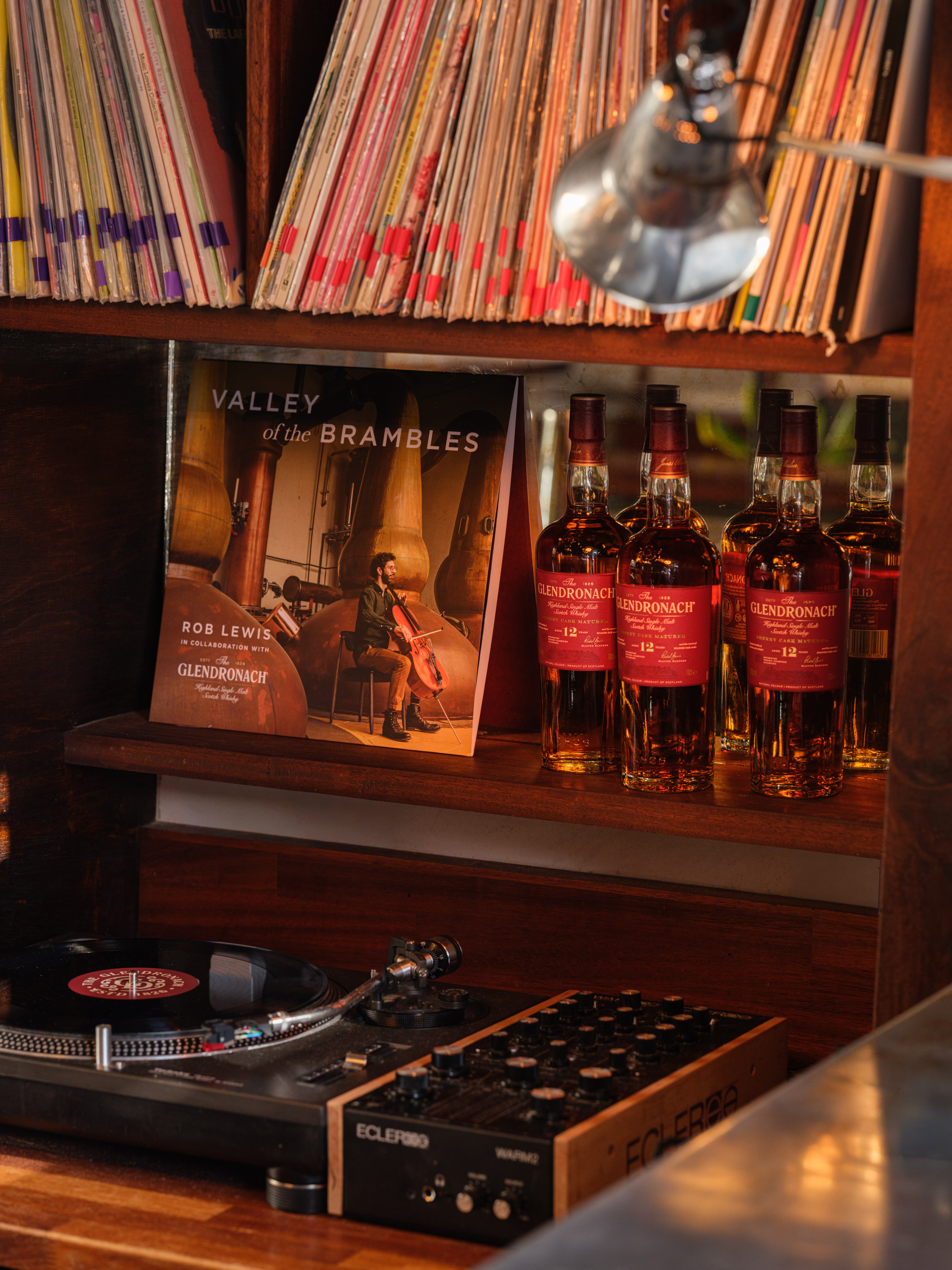 an image of an area of the bar which has record players and vinyl albums stacked across wooden shelves. On one of the shelves are bottles of the Glenronach 12 year old