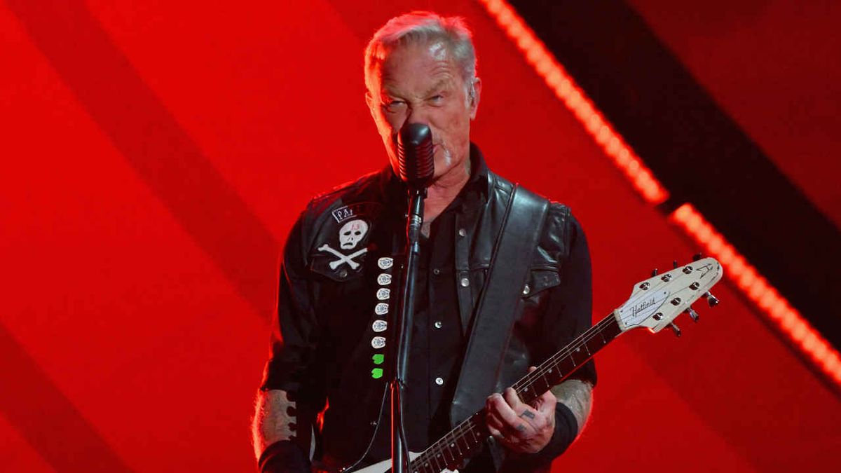 Metallica’s James Hetfield playing guitar onstage against a red backdrop