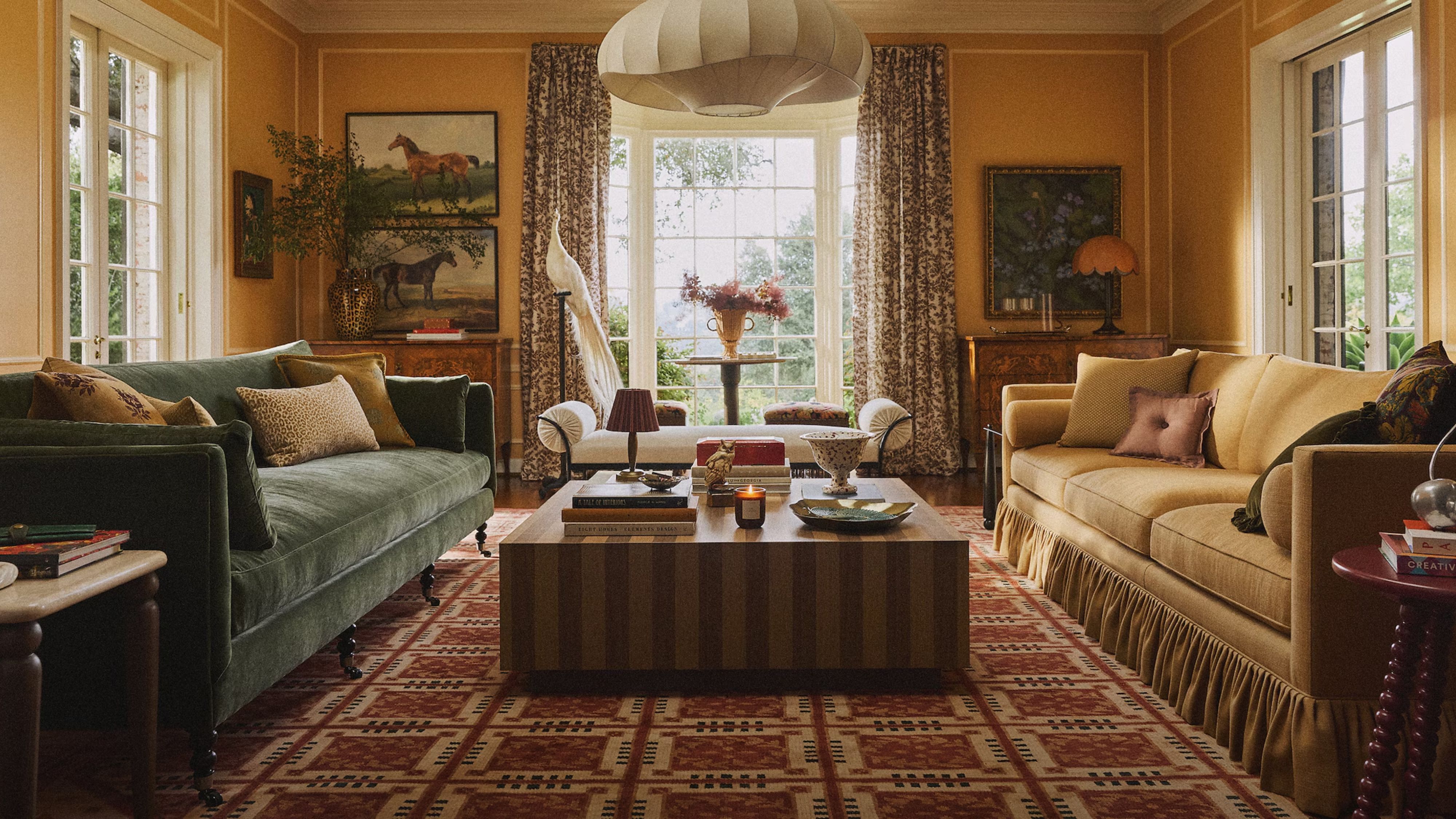 Richly layered fall living room featuring jewel-toned sofas, a striped coffee table, equestrian wall art, and several portable lamps.