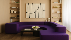 a living room with a large purple couch in front of a built in shelving unit with light wood shelves and a black and white painting