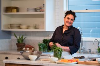 Samin Nosrat picks herbs while standing in her kitchen, in 'Salt Fat Acid Heat'