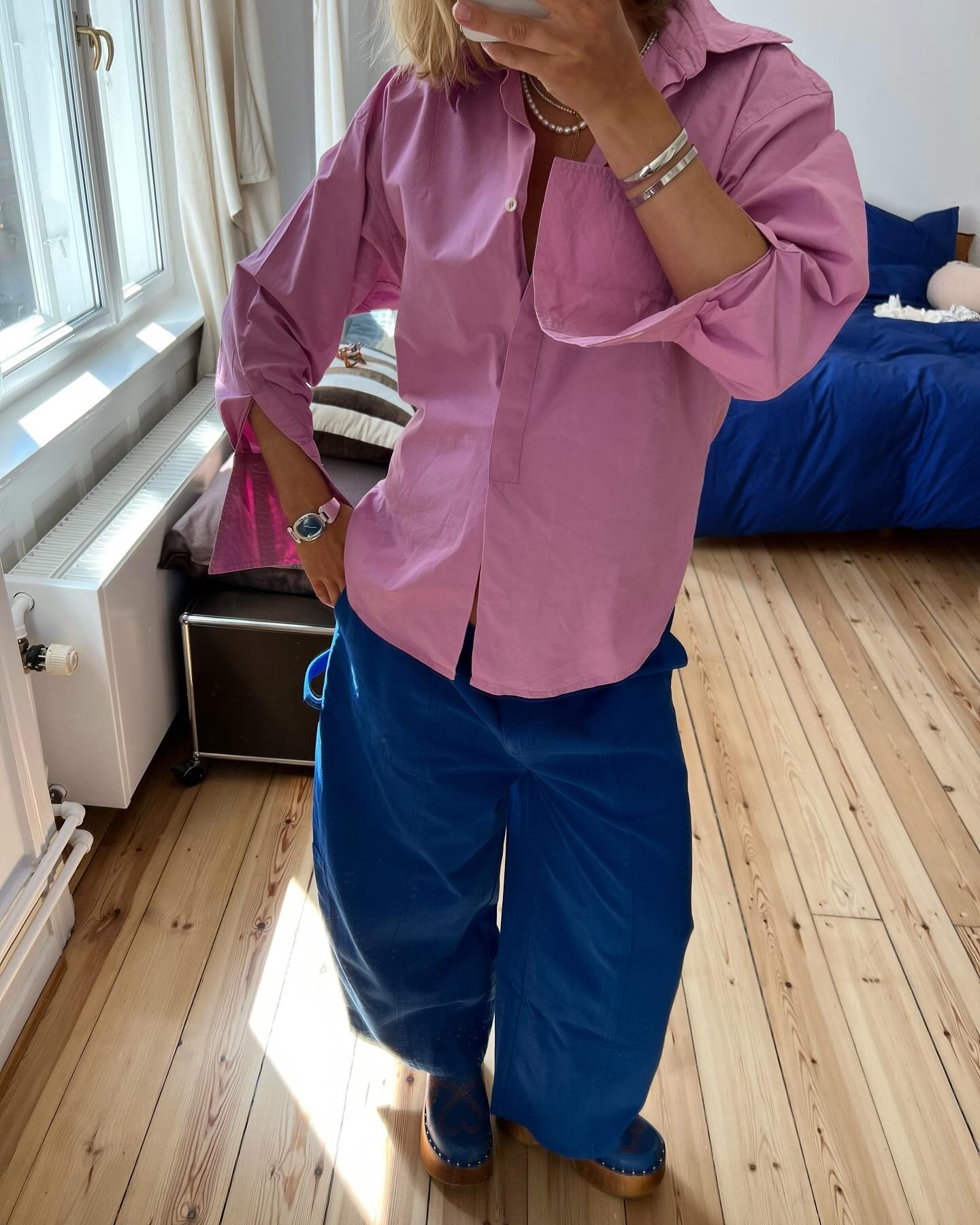 Influencer @amalienielsenn wears a pink skirt with colbat trousers and blue clogs.