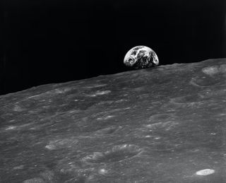 A black and white image of Earth rising over the moon