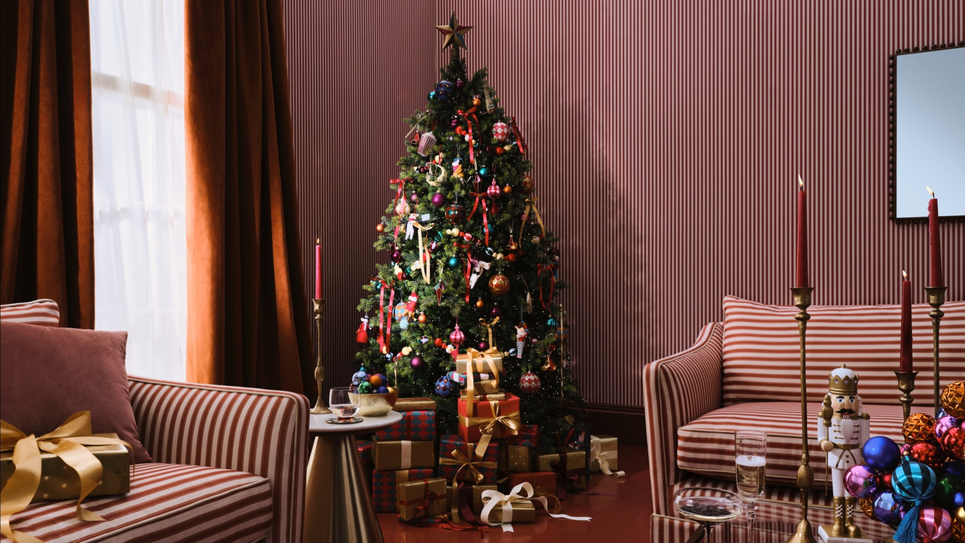 A living room with two striped sofas, a striped wallpaper and a Christmas tree decorated with decorations from the John Lewis Enchanted Tales range