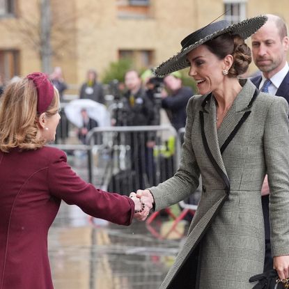 Princess Kate wearing a gray coat shaking hands with a woman