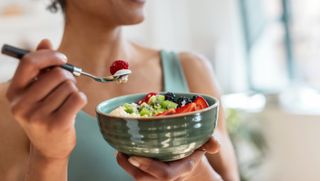 a woman eating from a bowl of fruit