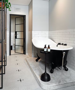 Monochrome bathroom with Crittall-style door and slipper bath