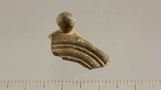 A fragment of the Roman dodecahedron — showing a stud and corner — against a gray background.