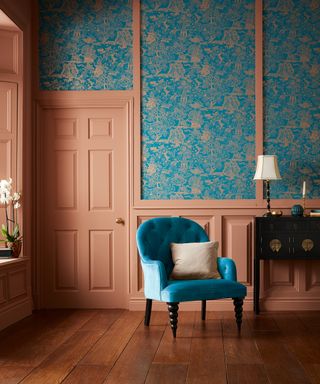 A blue patterned wallpaper and rust-colored wall panelling and doors demonstrate how to hang wallpaper.
