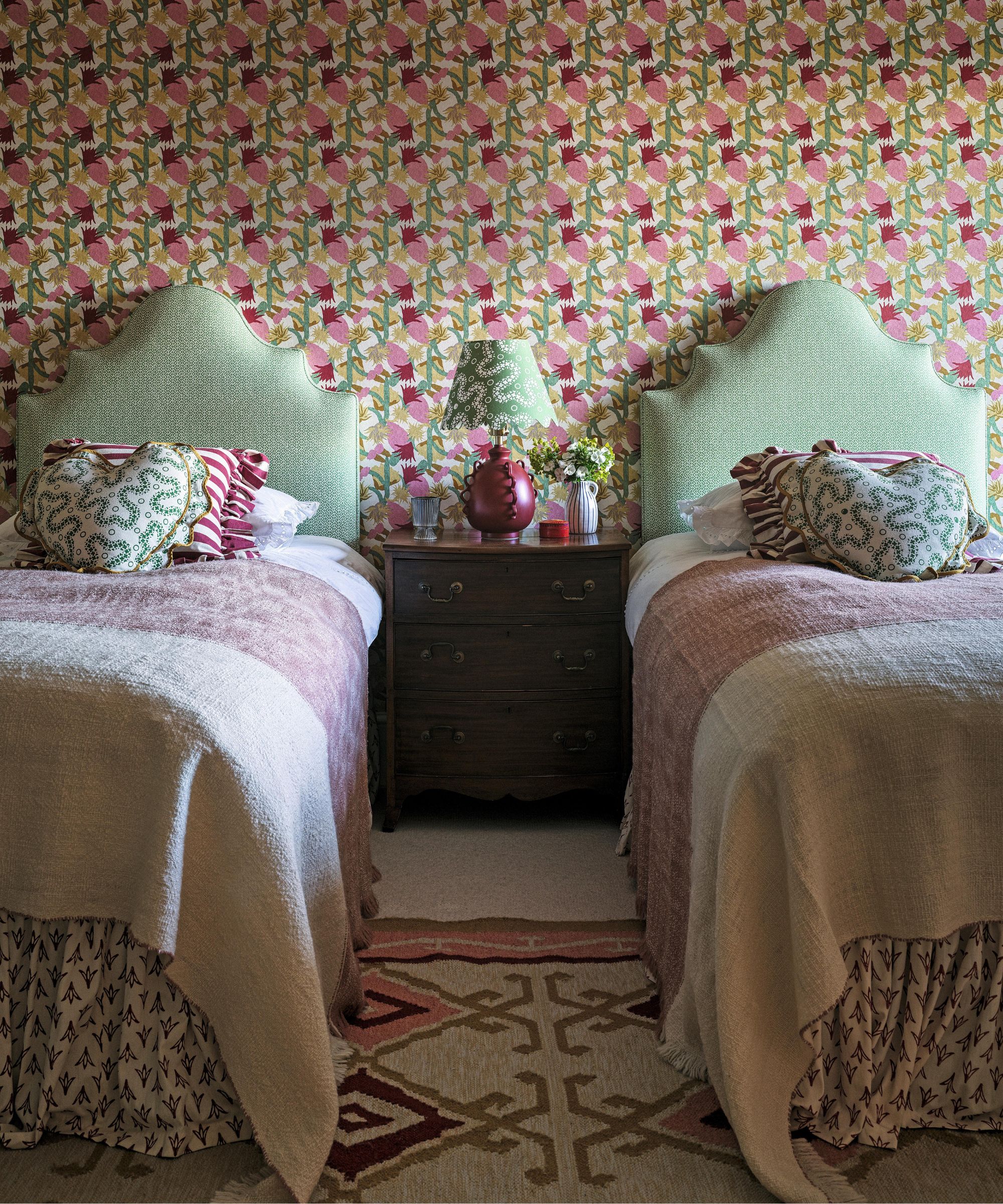 a pink and green wallpapered bedroom with twin beds
