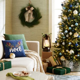 Traditional Christmas tree with blue accents and wreath on the wall