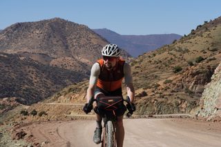 Image shows Stefan riding up the Tizi n'Telouet gravel pass in Morocco