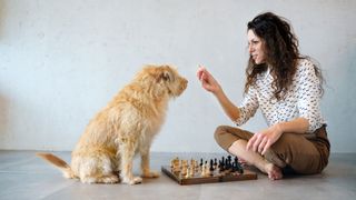 Woman playing chess with her dog