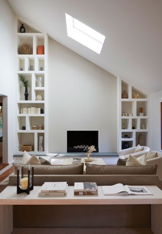 open plan living room in pale cream colours, modern fireplace, fitted shelving and console table
