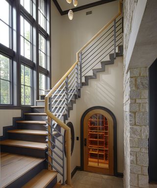 hallway with gray and wooden stairs, metal staircase and arched doorway