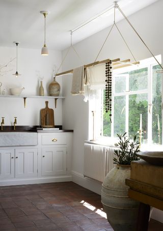 A utility room with white cabinetry , open shelving, and a laundry maid drying rack hanging from the ceiling