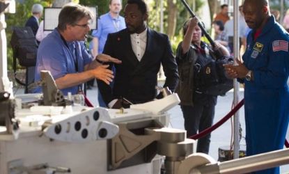 Musician Will.i.am listens to NASA Goddard Space Flight Center Sciences and Exploration Directorate chief scientist Jim Garvin next to a mock up of the Mars Science Laboratory rover Curiosity