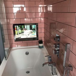 Bathroom with pink tiles inbuilt tv and bathtub