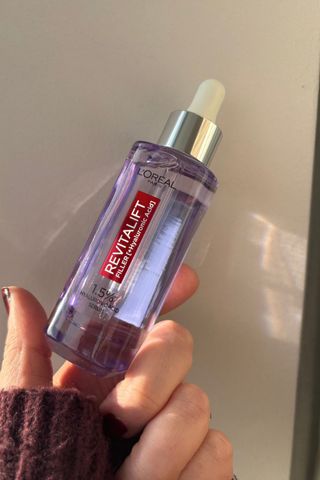 a hand holding loreal hyaluronic acid serum bottle