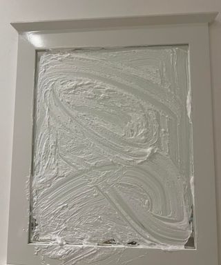 A mirror covered in shaving foam with a white wooden border