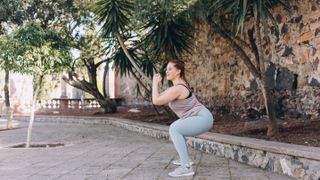Woman outside doing body squats