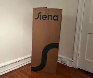 The Siena Memory Foam Mattress in a box against a white wall.