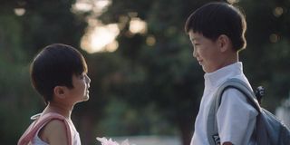 Two school-aged Chinese boys, one with a pink backpack and one grey, smiling at each other in The Little Prince(ss)