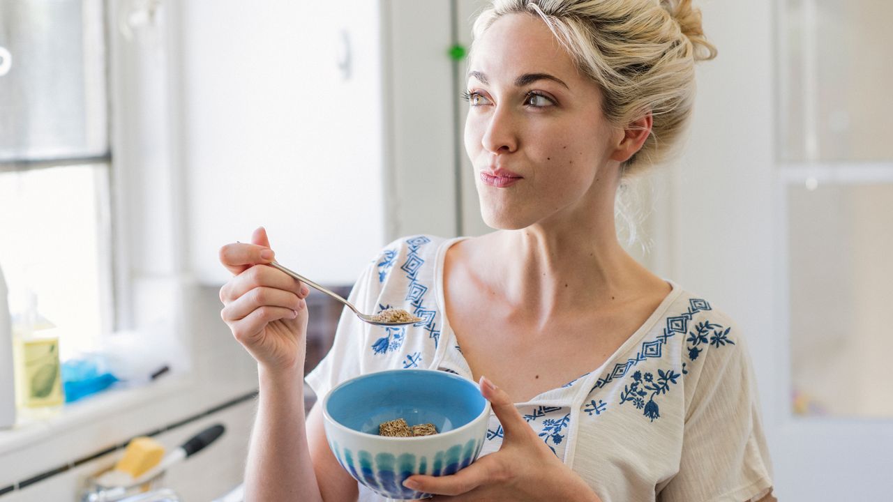 Woman smiles as she tucks into a bowl of food