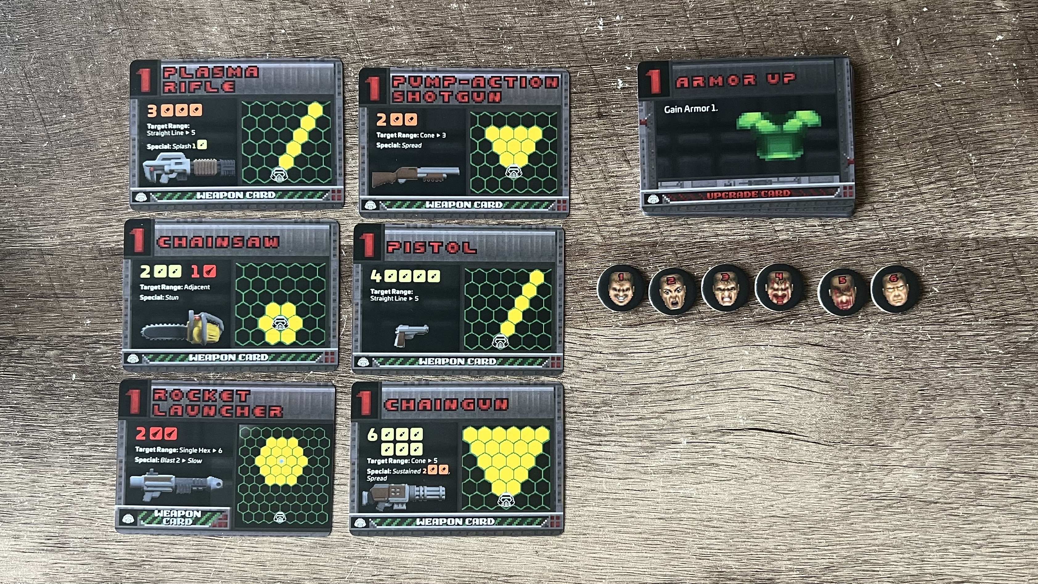 Close up on weapon and upgrade cards, with health counters on a wooden desk