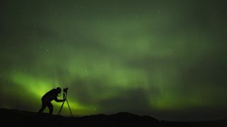 silhouette of photographer shooting aurora
