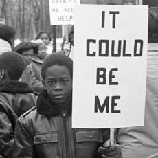 A young boy holding a sign that reads, "It could be me."
