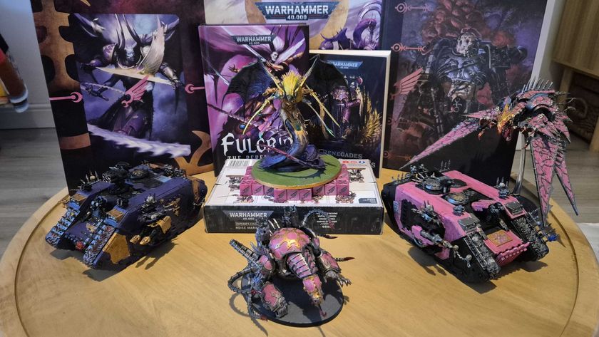 Warhammer Emperor&#039;s Children models, vehicles, boxes, and books on a circular wooden table