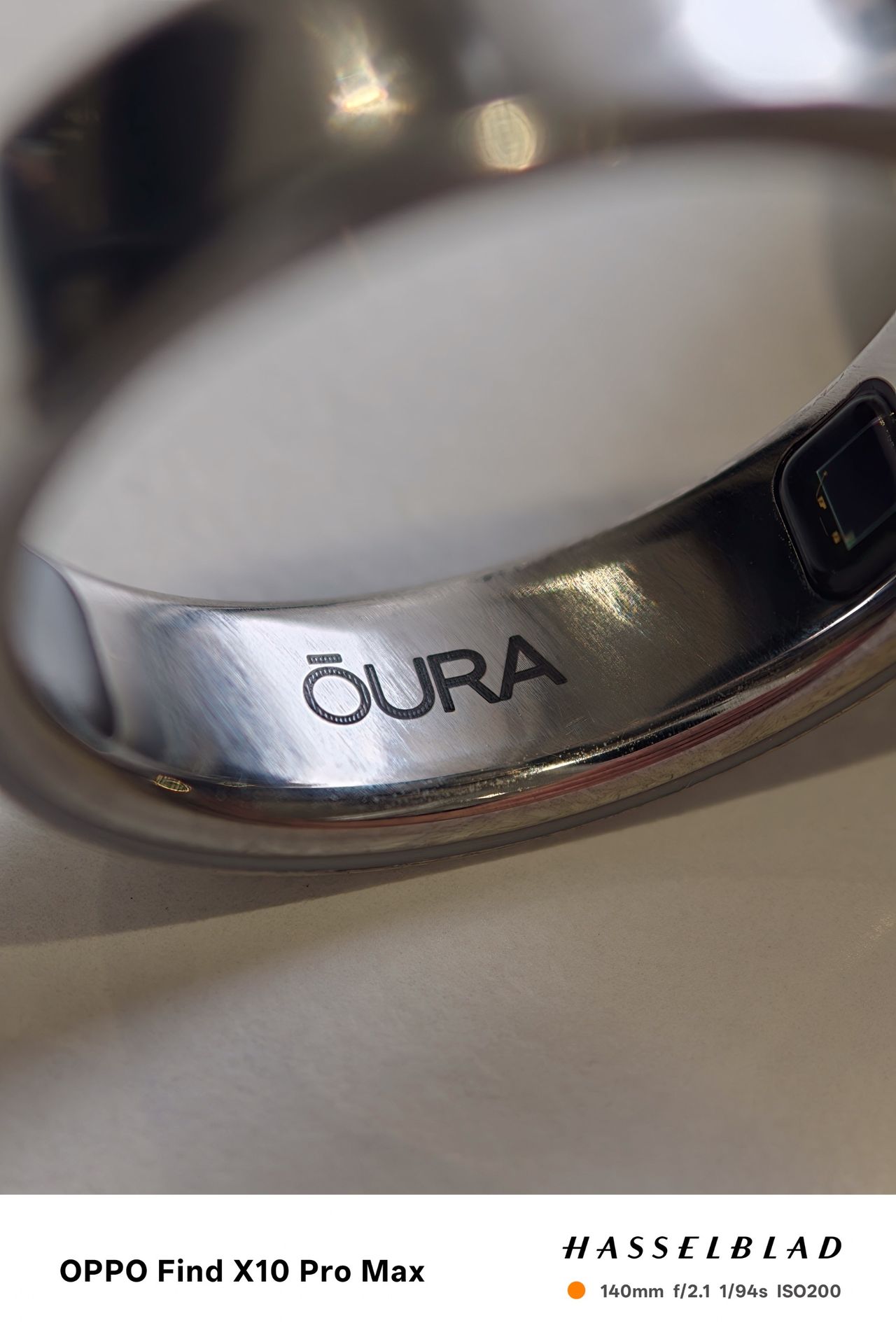 Macro close-up of the polished metal surface and logo on an Oura Ring.