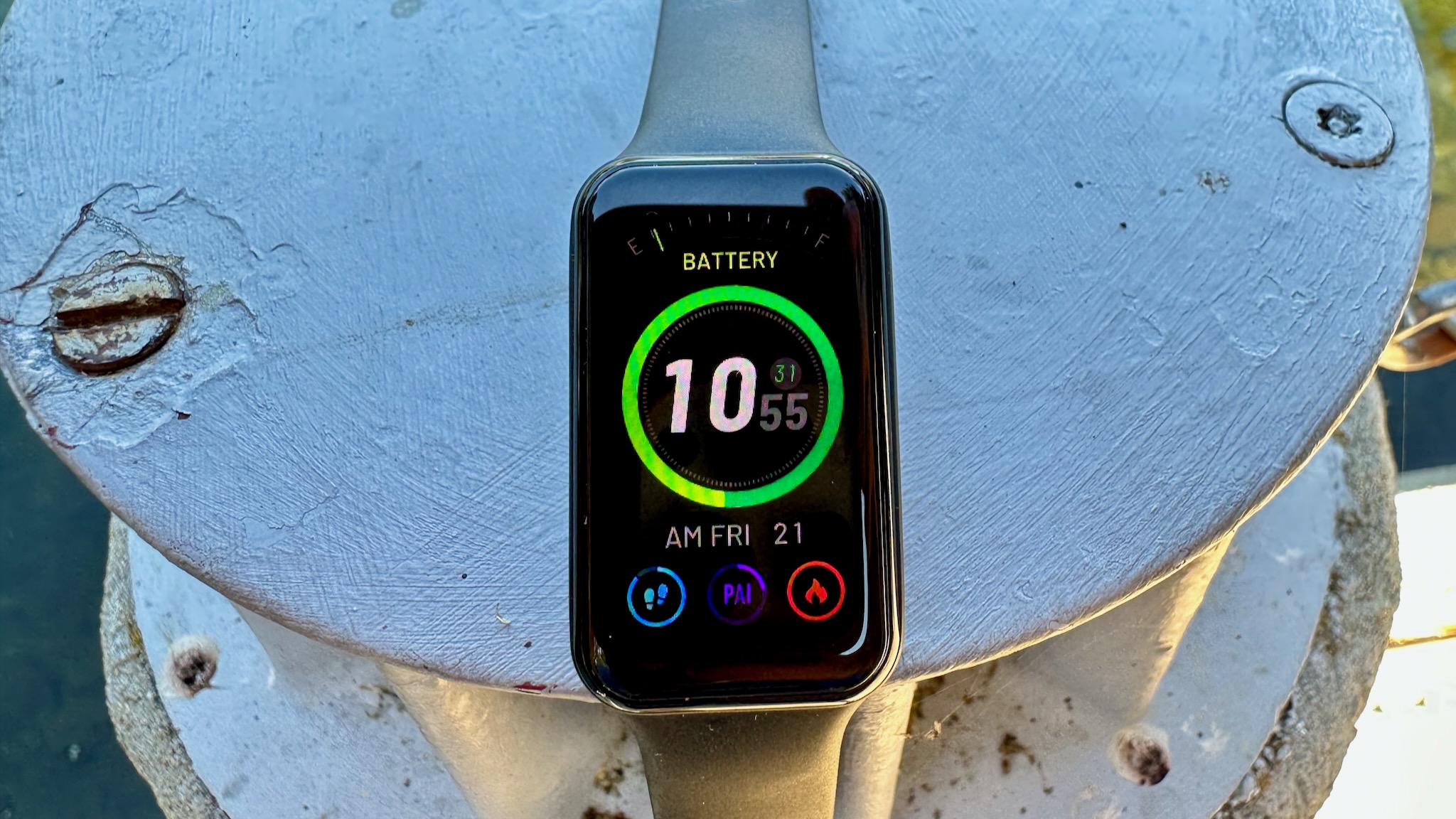 An Amazfit Band 7 showing a low battery, daily steps, PAI score, and intensity minutes on a watch face.