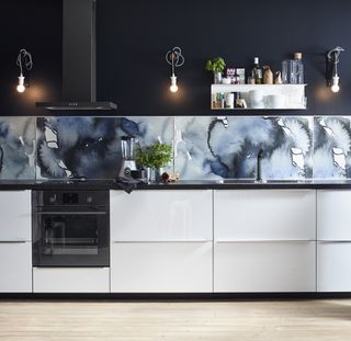 An Ikea kitchen with a blue patterned backsplash in a modern monochrome black and white gloss handleless kitchen