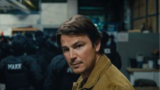 Josh Hartnett looking to the side with caution as he stands behind a SWAT team in Trap.