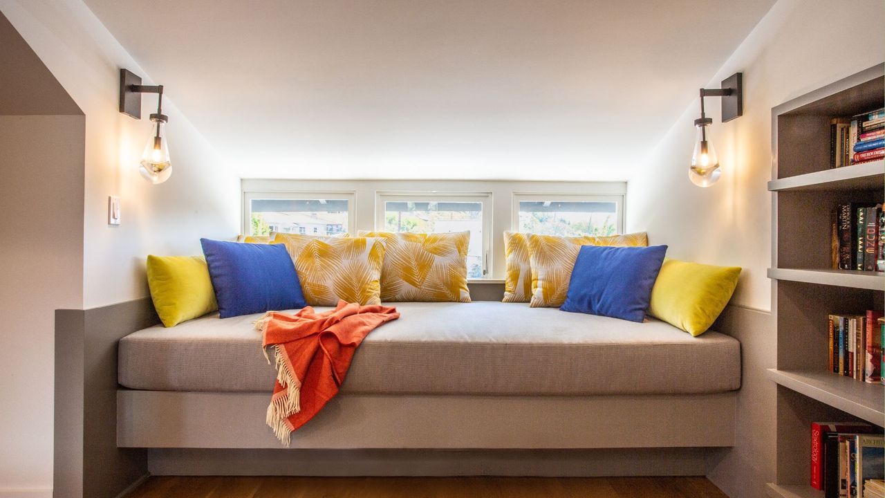 A sofa bed in an attic with shelves for book storage 