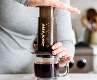 An AeroPress on a countertop, sat on a clear cup of coffee
