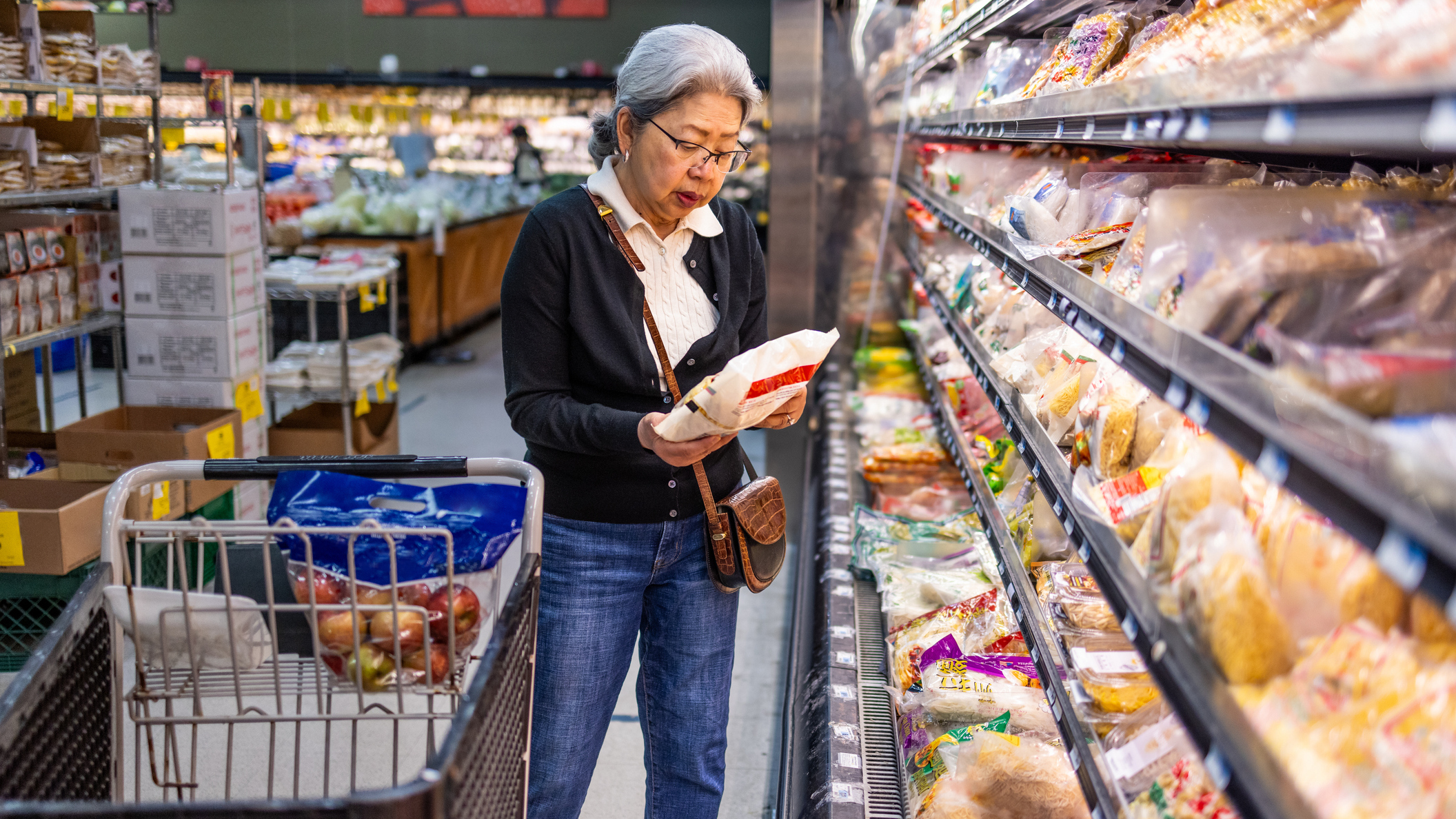 Senior woman looks at packet in grocery store