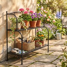 IKEA LACKO Shelf Unit holding a basket of tools and plants of flowers and foliage in a garden