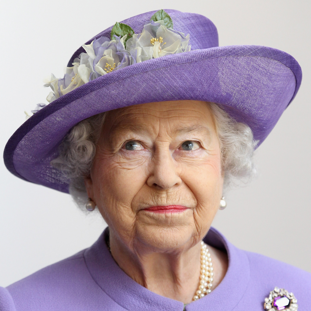 Queen Elizabeth wearing a purple hat and smirking