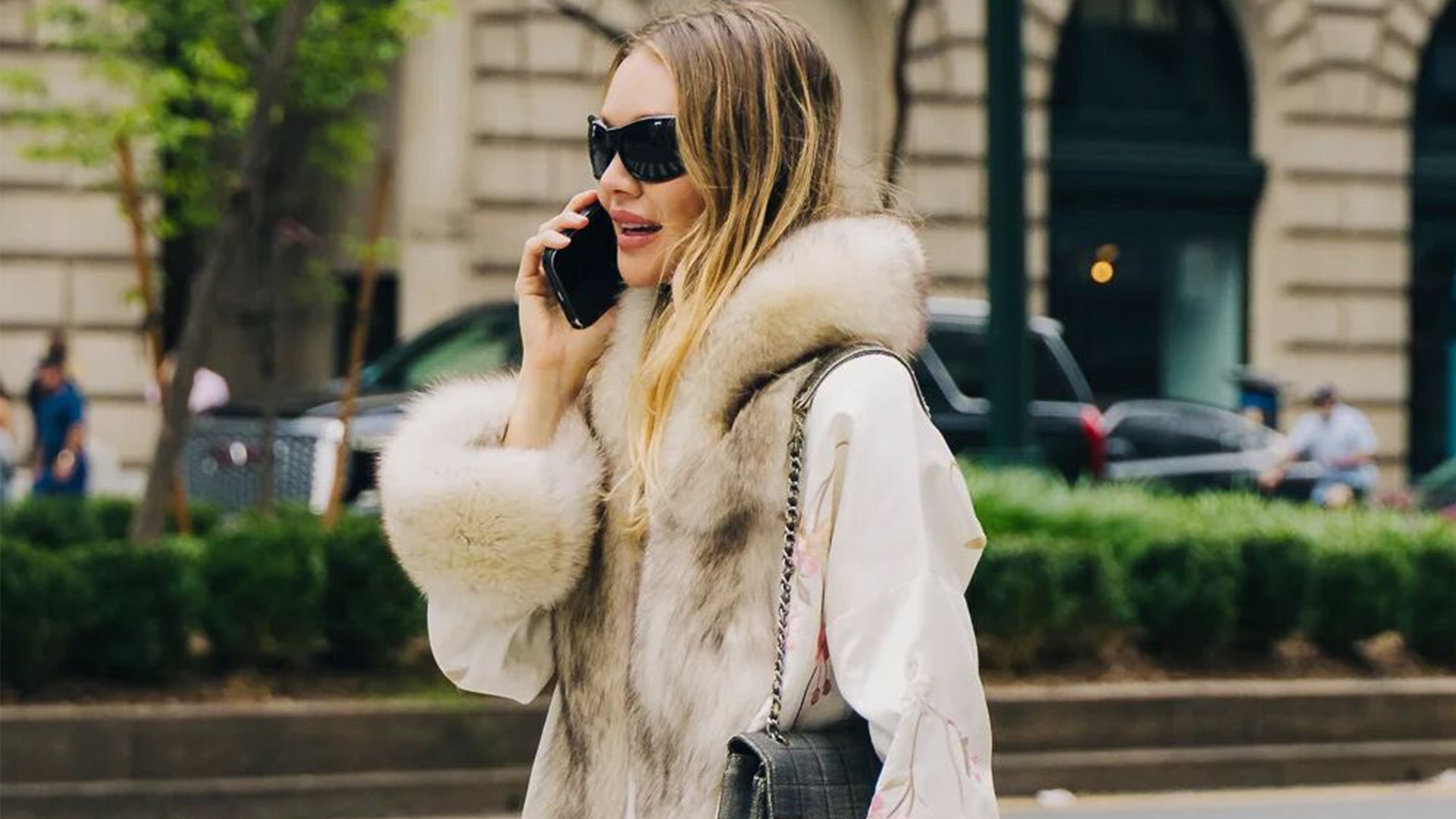 Woman wearing a fur-trimmed coat and black sunglasses.
