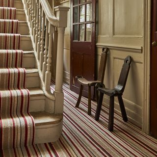 Red and beige carpet in hallway with beige stair case with matching red and beige stair case runner