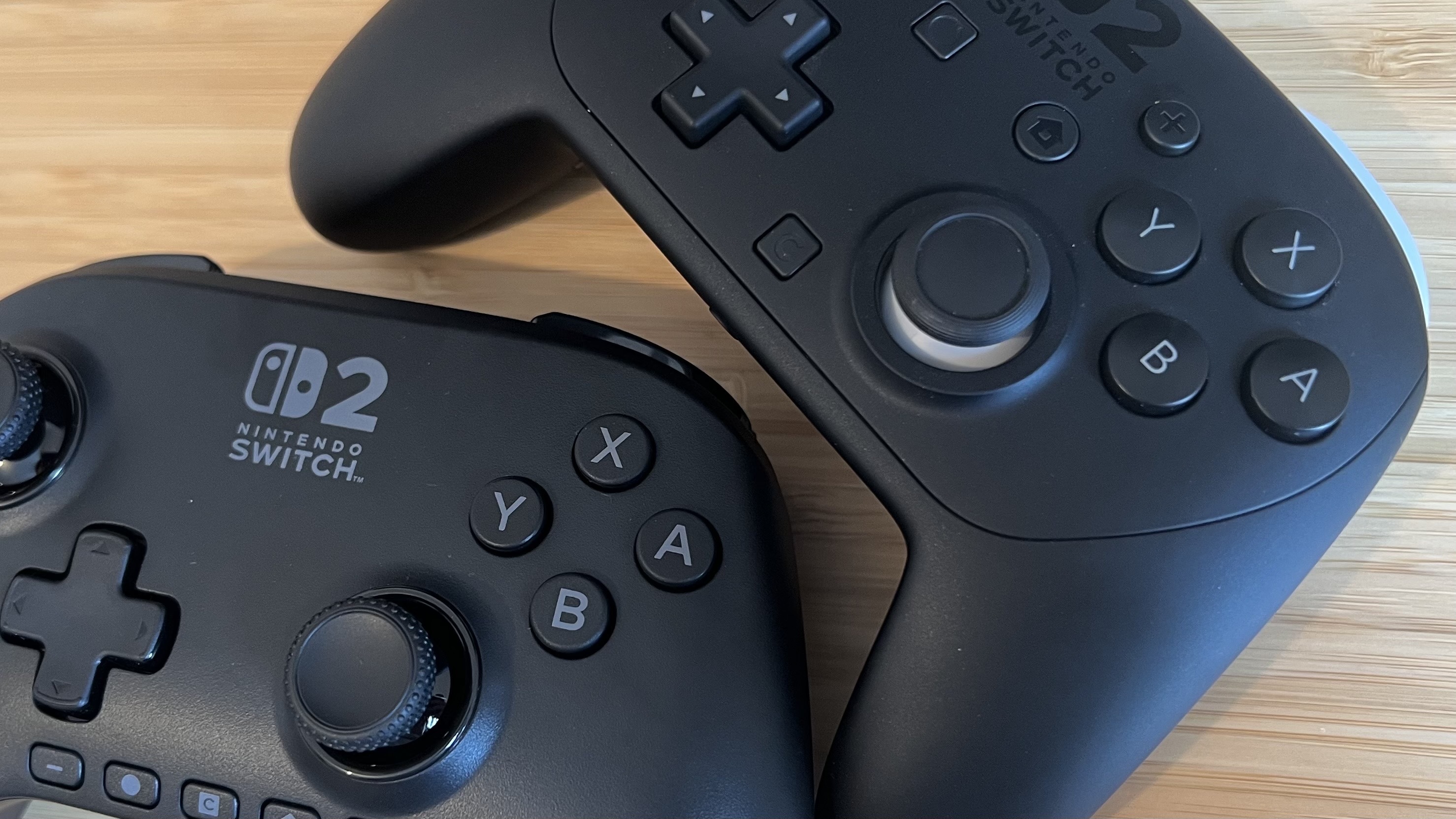 Close up on face buttons and thumbsticks of both the PowerA Advantage Nintendo Switch 2 Controller and Nintendo Pro Controller